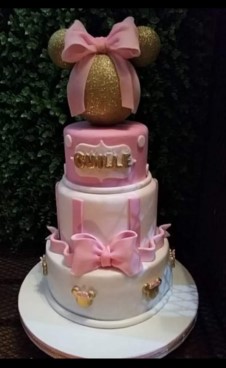 Torta artesanal con temática infantil Minnie de tres pisos. Colores rosa, blanco y dorado.